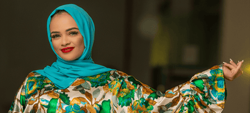 Woman in a bright blue hijab and floral abaya posing confidently indoors