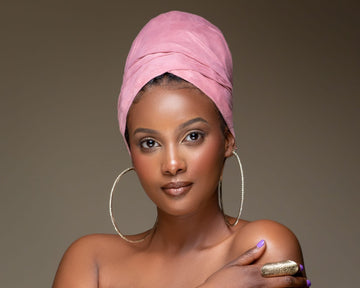 Woman wearing a stylish pink headwrap, gold hoop earrings, and a statement ring
