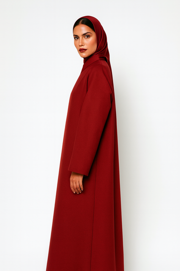 Woman wearing a red modest abaya and matching hijab, posed against a white background