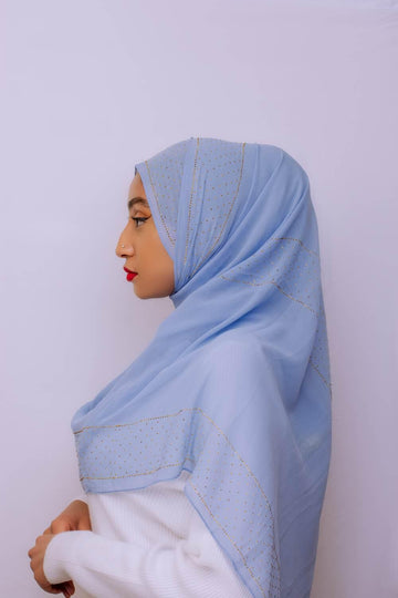 Woman in profile wearing a light blue embellished hijab and white modest top