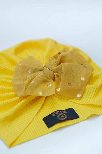 Yellow ribbed baby turban with a sheer polka dot bow on a white background